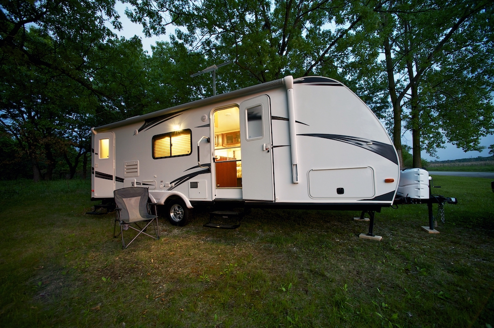 Travel trailer set up at a campsite at dusk.
