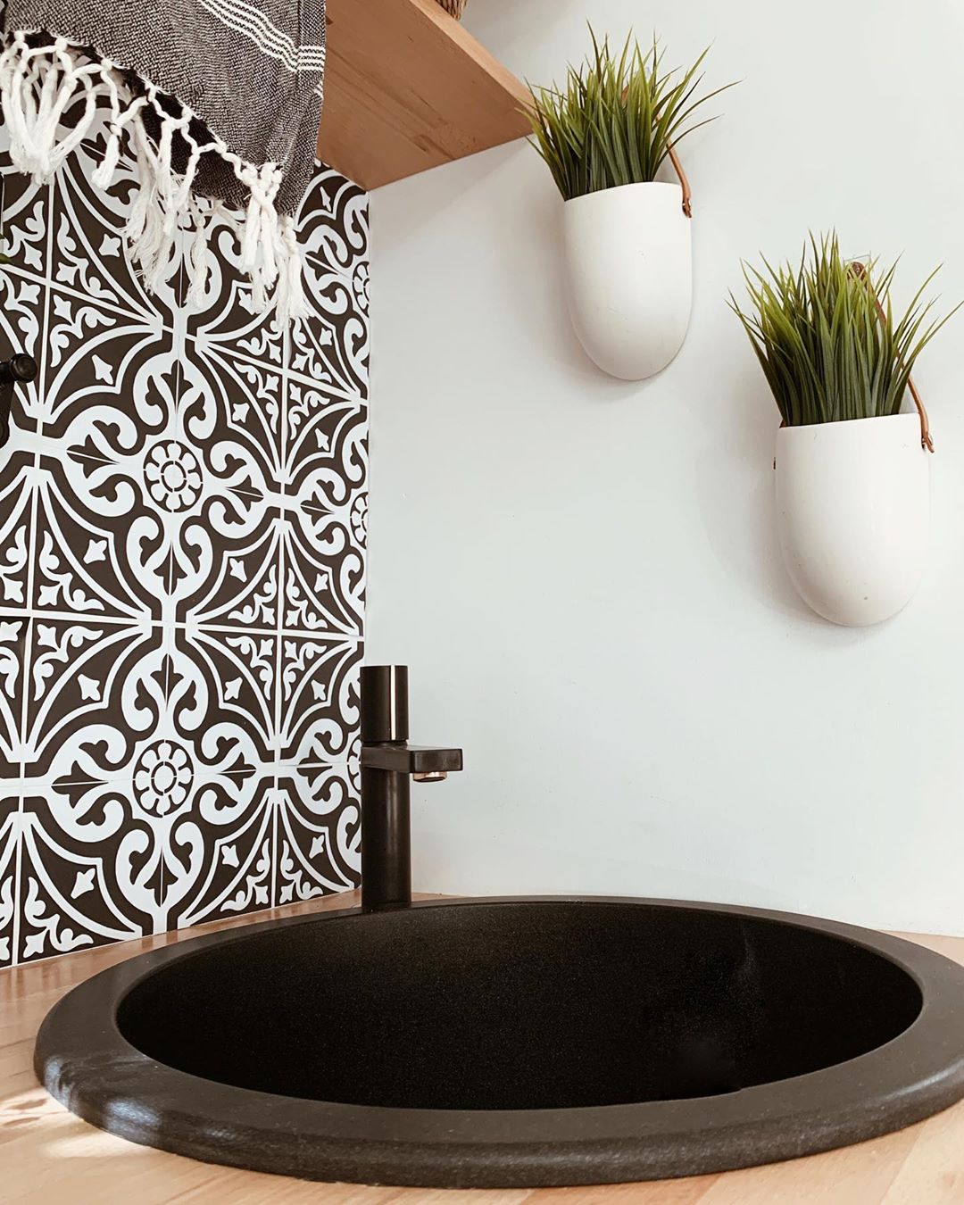 Black and white splashback behind a black RV sink and tap