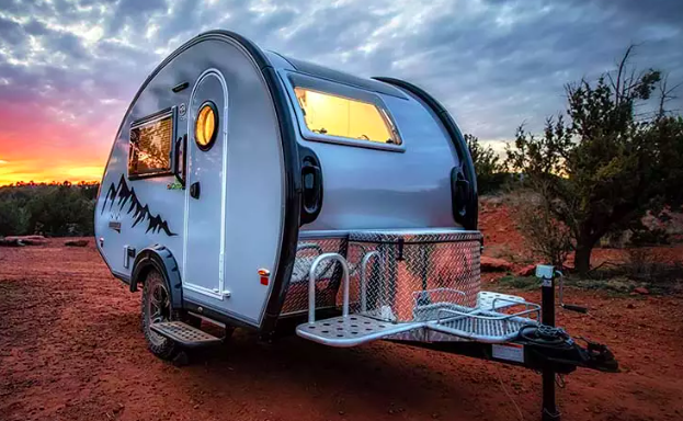 Exterior view of a nuCamp TAB 320S teardrop camper with a striking orange sky in the background.