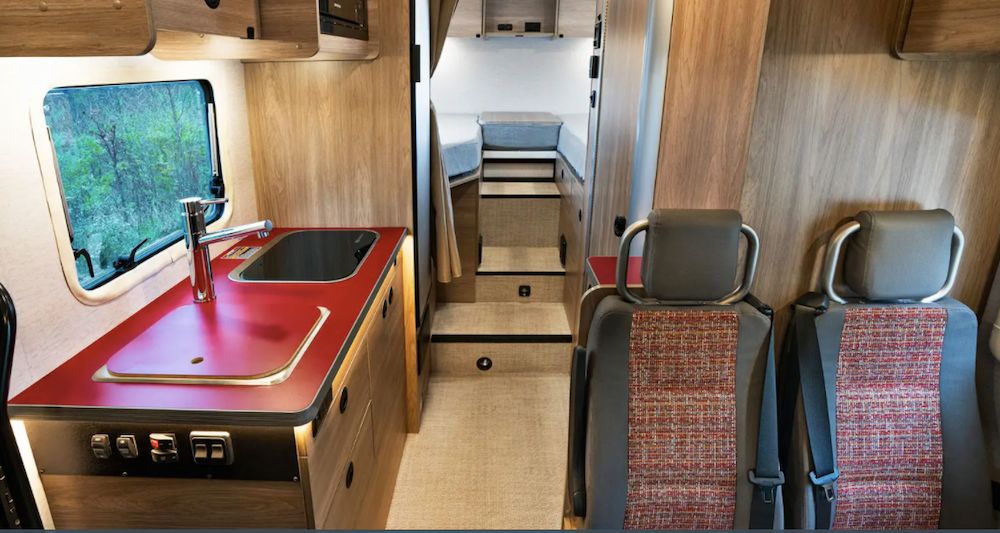 Wooden interior of small RV with a rich red kitchen countertop