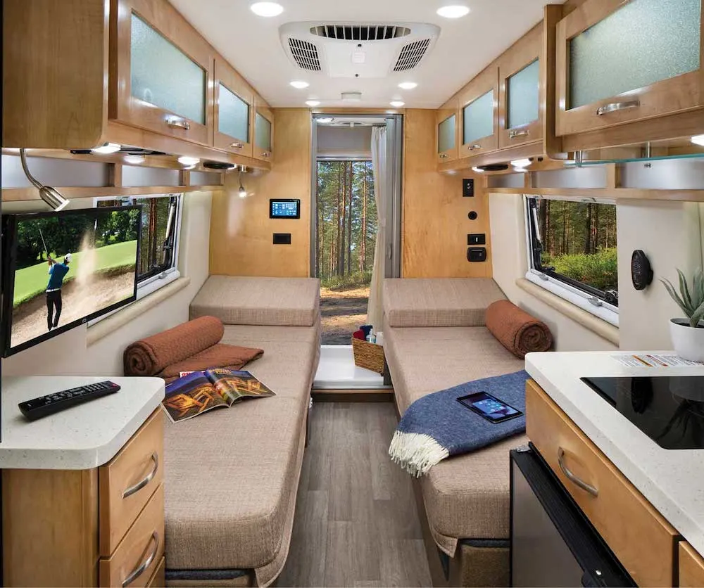 Interior of a beige/brown camper van, looking towards the rear doors, showing a bench seat on each side.