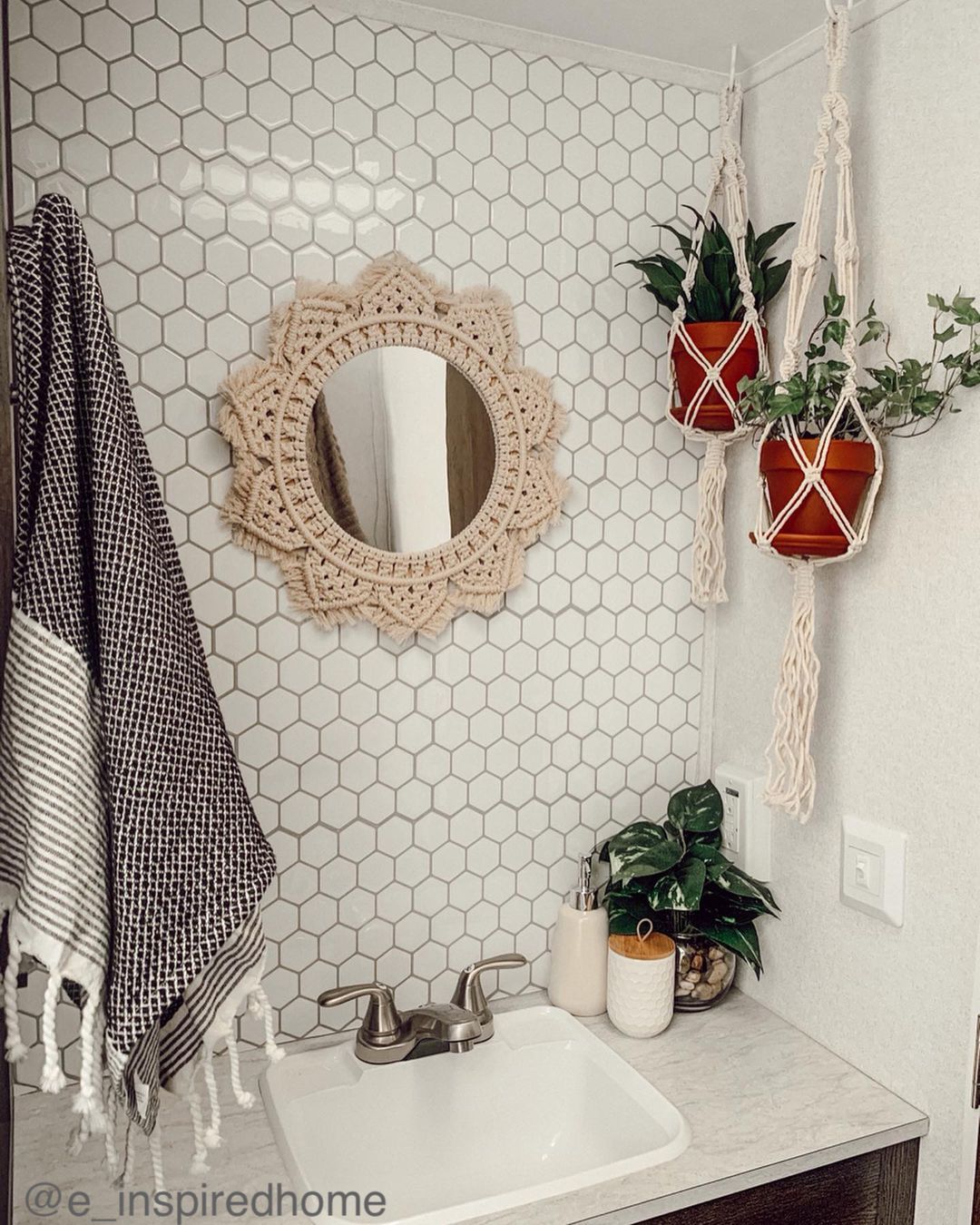 Small round mirror with macrame frame and hanging plants in a small camper bathroom.
