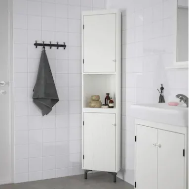 White cabinet in the corner of a white bathroom.